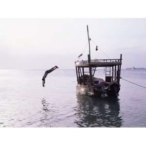  Boy in Mid Air Diving from a Boat Moored by the Beach at 